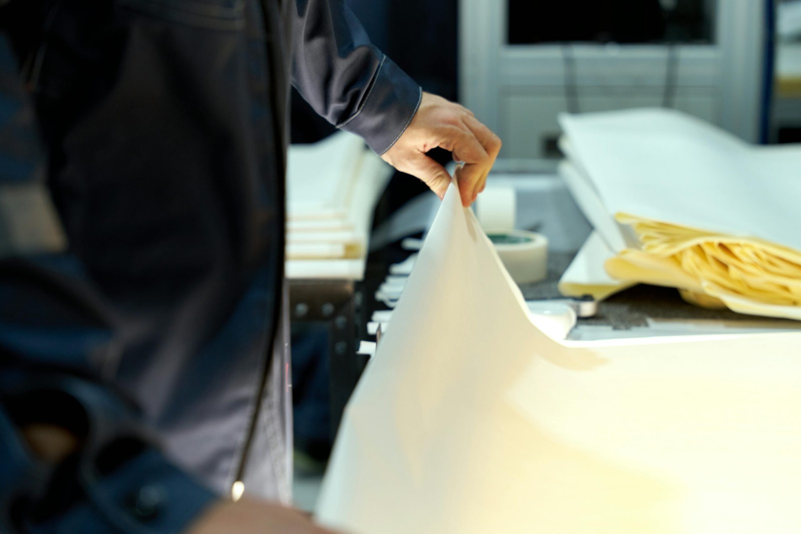 Paper An industrial worker manages large sheets in a manufacturing setting, focusing on precision and quality.