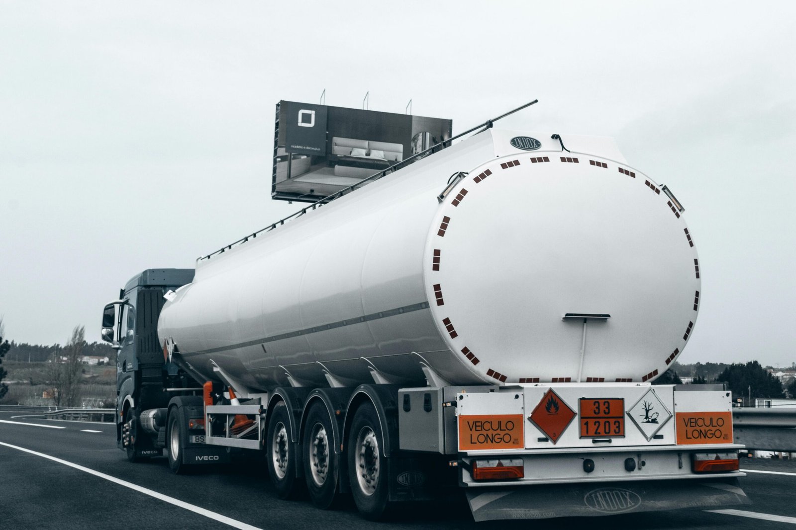 Other Industries Rear view of a large tanker truck transporting fuel on a highway, emphasizing logistics and transportation.